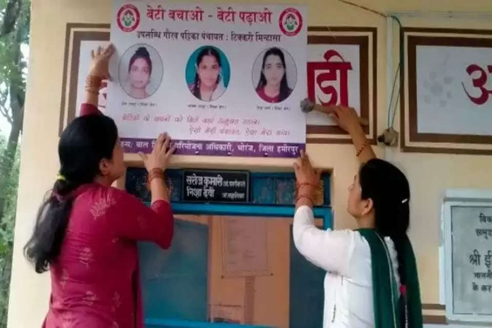 सुंगरवाड़ में बेटियों का उपलब्धि पोस्टर लगातीं आंगनबाड़ी कार्यकर्ता